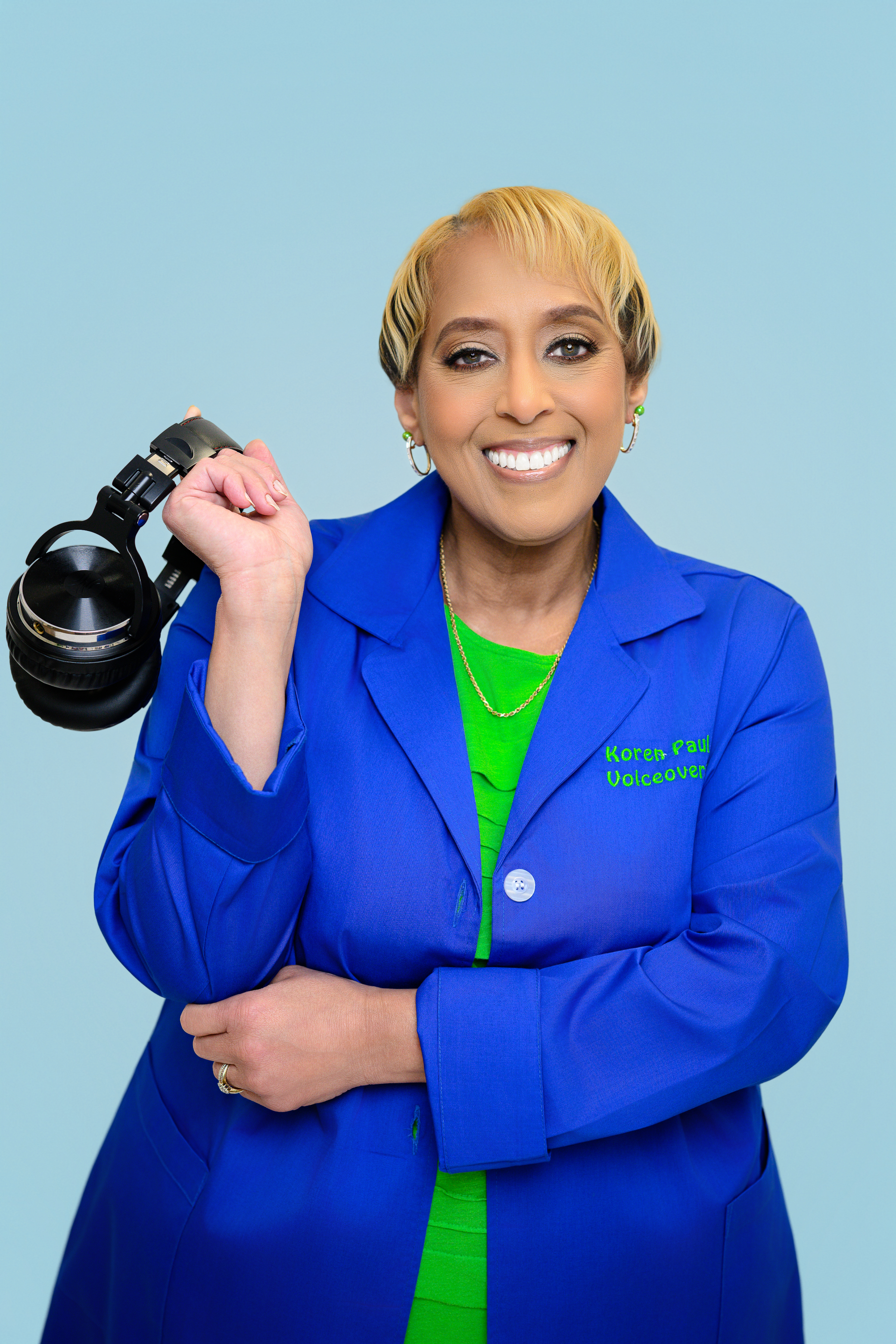 Photo is of a smiling woman with short blond and dark brown hair holding headphones in right hand with arm bended up, left arm is across her waist with hand under the right elbow. She is wearing a cobalt blue lab coat with a lime green blouse. Written above her head is "Smart, Smooth, Confident" and "The intelligent prescription for your story."